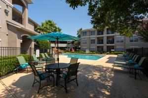Apartments For Rent in Houston, TX - Pool and Patio with Lounge Chairs, Umbrella, Table and Chairs